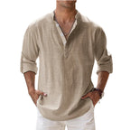 Man wearing a beige linen shirt with rolled-up sleeves against a light blue background