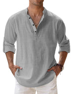 Man wearing a gray shirt with rolled-up sleeves against a light blue background