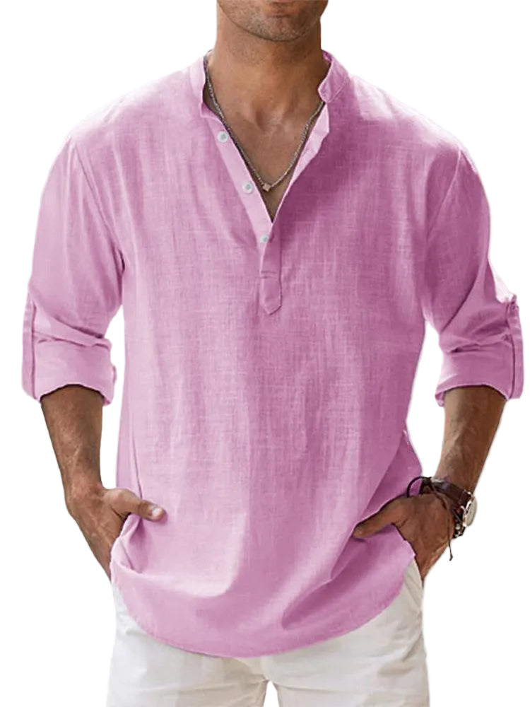 Man wearing a pink shirt with rolled-up sleeves against a light background