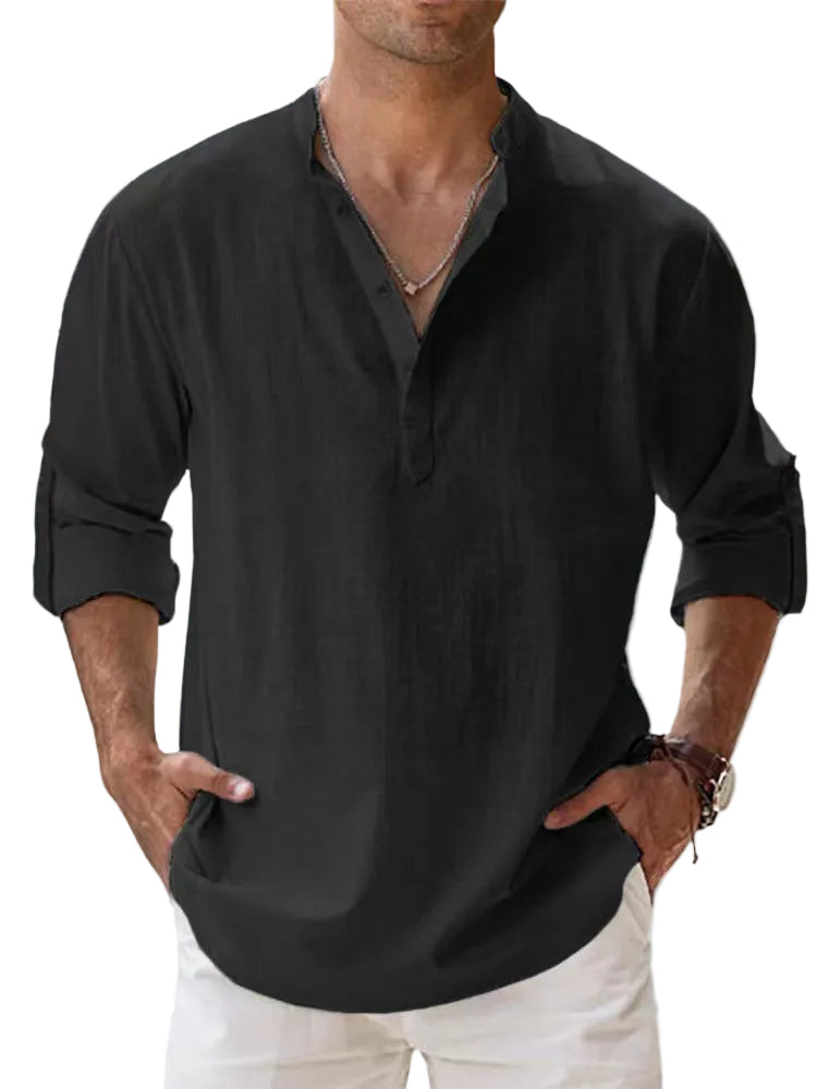 Man wearing a black shirt with rolled-up sleeves against a light background