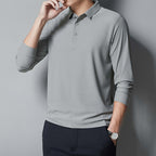 Person wearing a gray long-sleeve polo shirt against a gray background