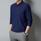 Person wearing a navy blue long-sleeve polo shirt and gray pants against a gray background