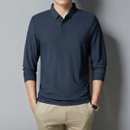 Person wearing a navy long-sleeve polo shirt against a gray background