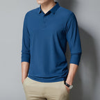 Person wearing a blue long-sleeve polo shirt against a gray background
