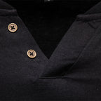 Close-up of a black garment with gold buttons on a dark background